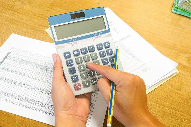 woman using a calculator and laptop